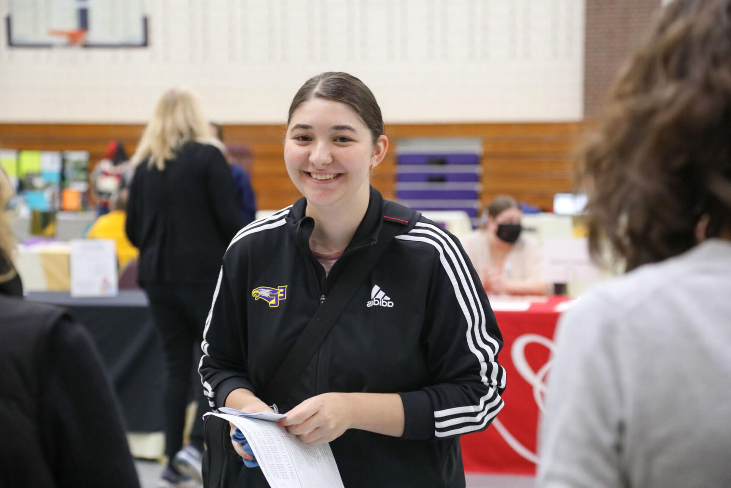 A female student smiles while visiting a booth at the Community 参与ment Fair